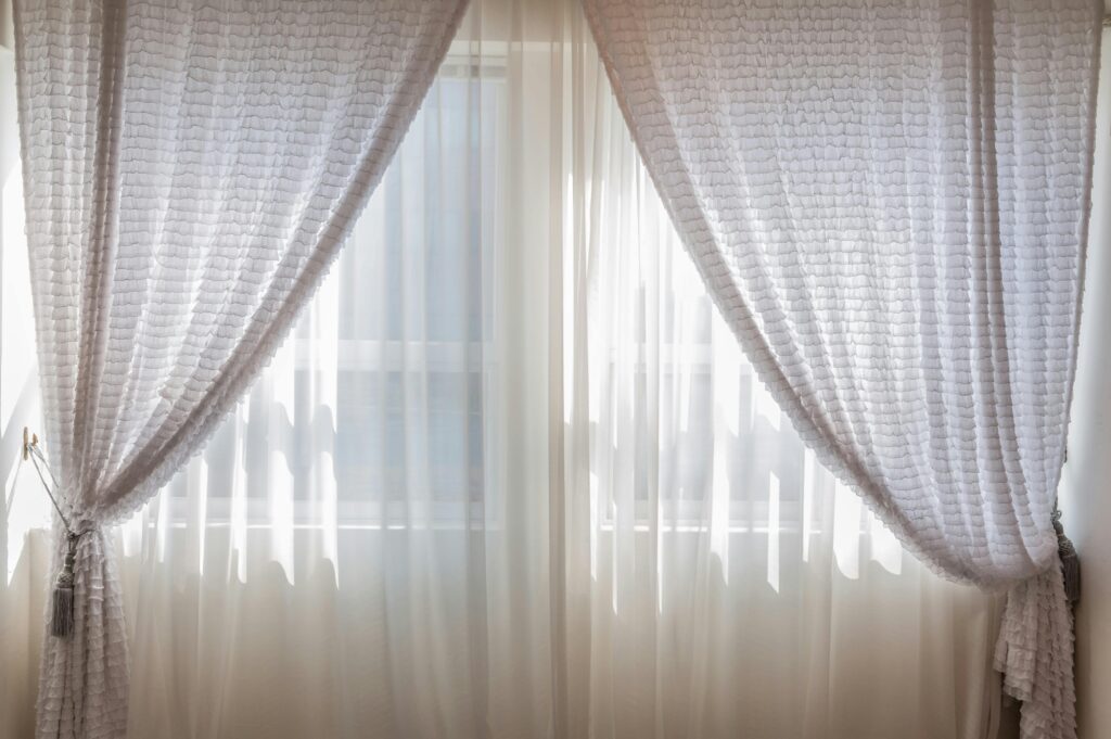 Sun shining through elegant white curtains in a cozy, modern interior setting.